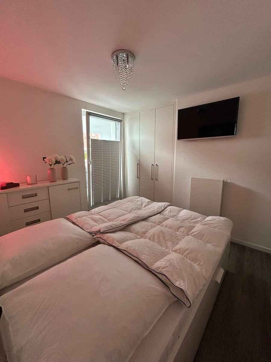 Schlafzimmer mit Doppelbett, Kleiderschrank und Fernseher an der Wand.
