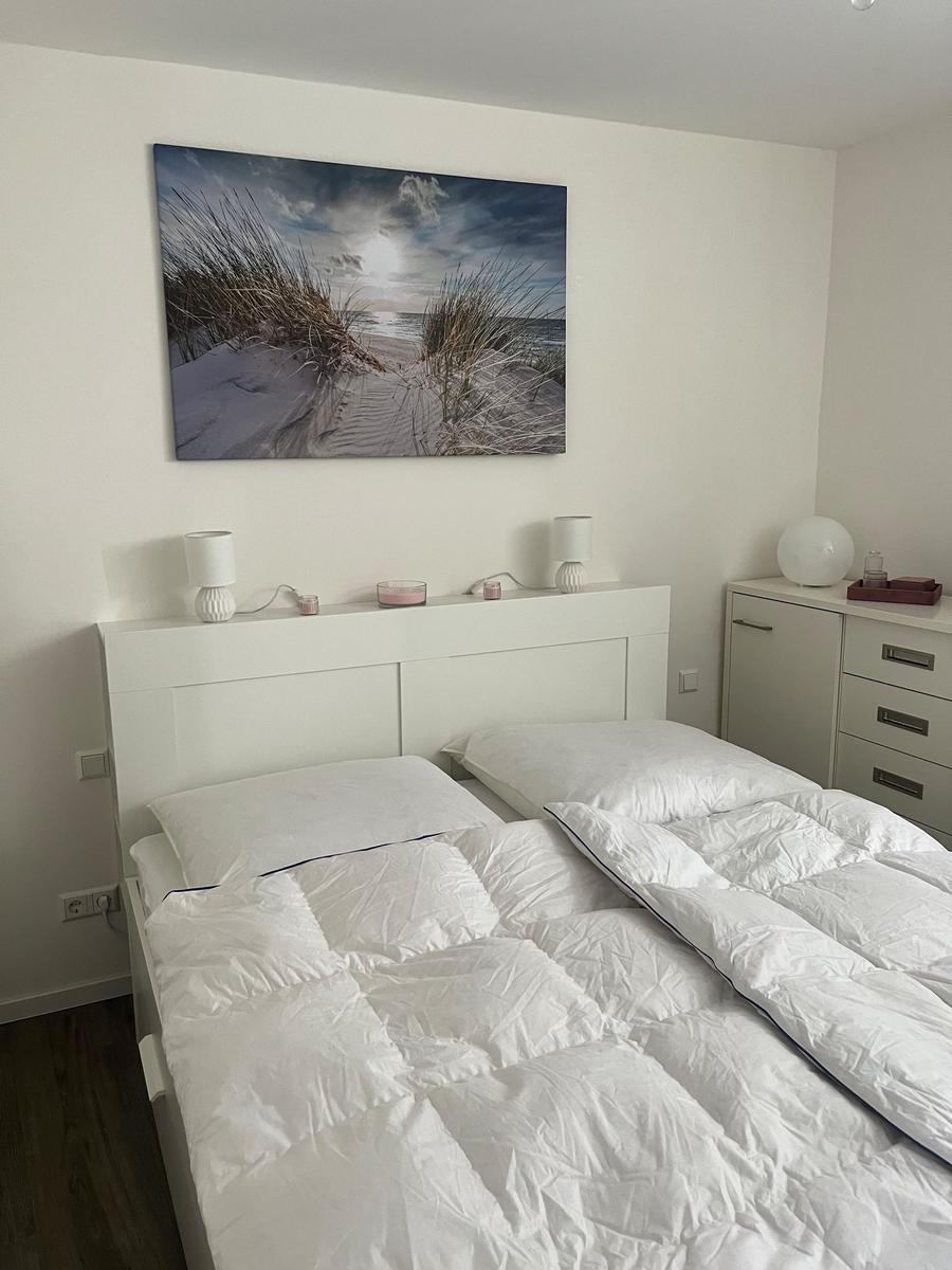Schlafzimmer mit weißem Bett, Wandbild und Nachttisch