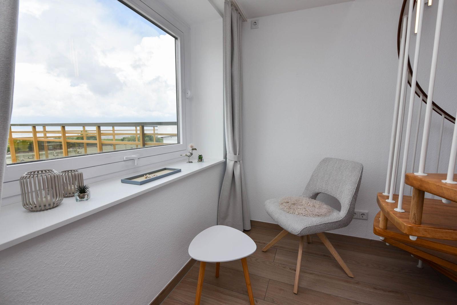 Raum mit Stuhl, Tisch und Fenster mit Blick auf Balkon.