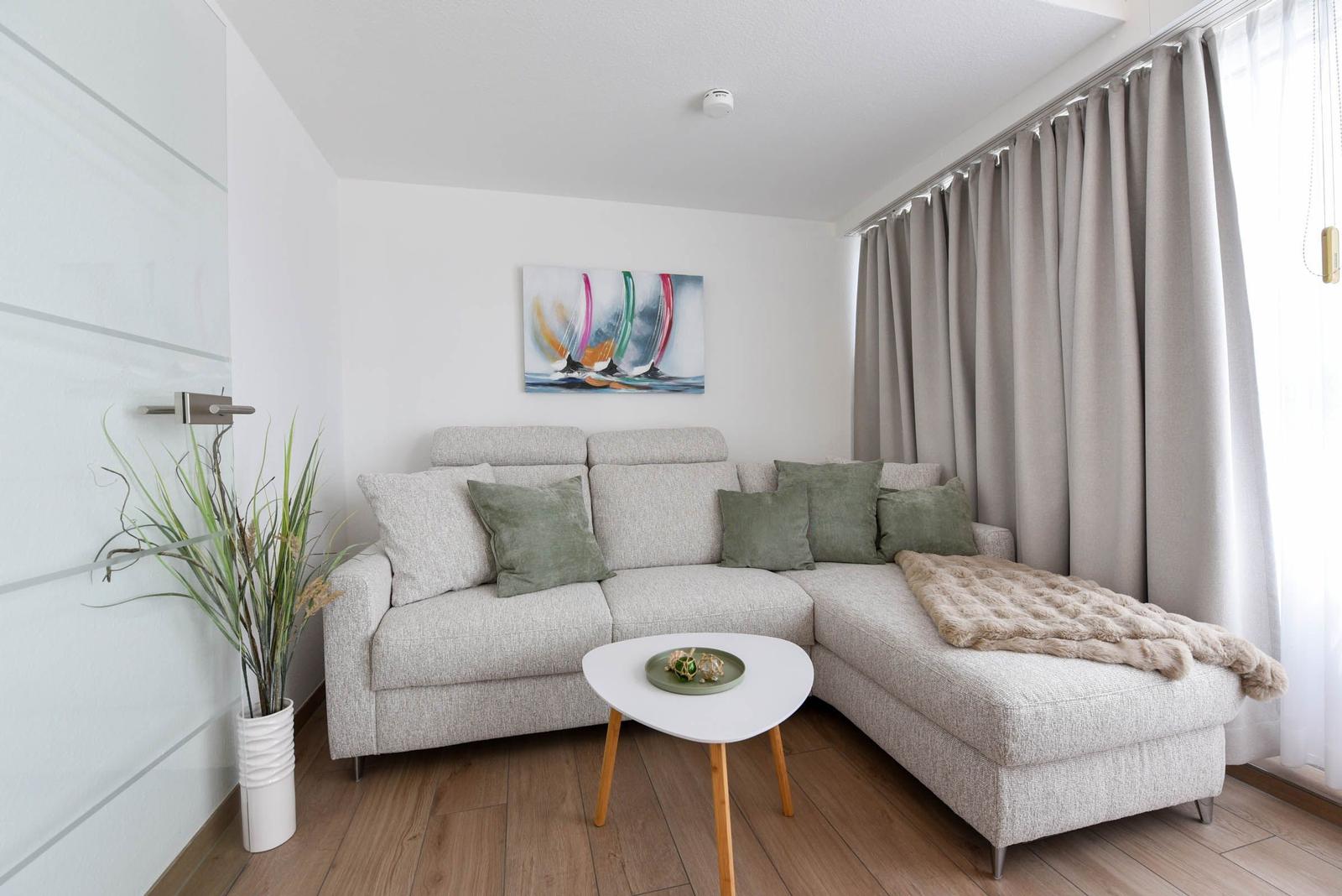 Ein Wohnzimmer mit einem hellen Sofa, einem runden Tisch und einem Wandbild.