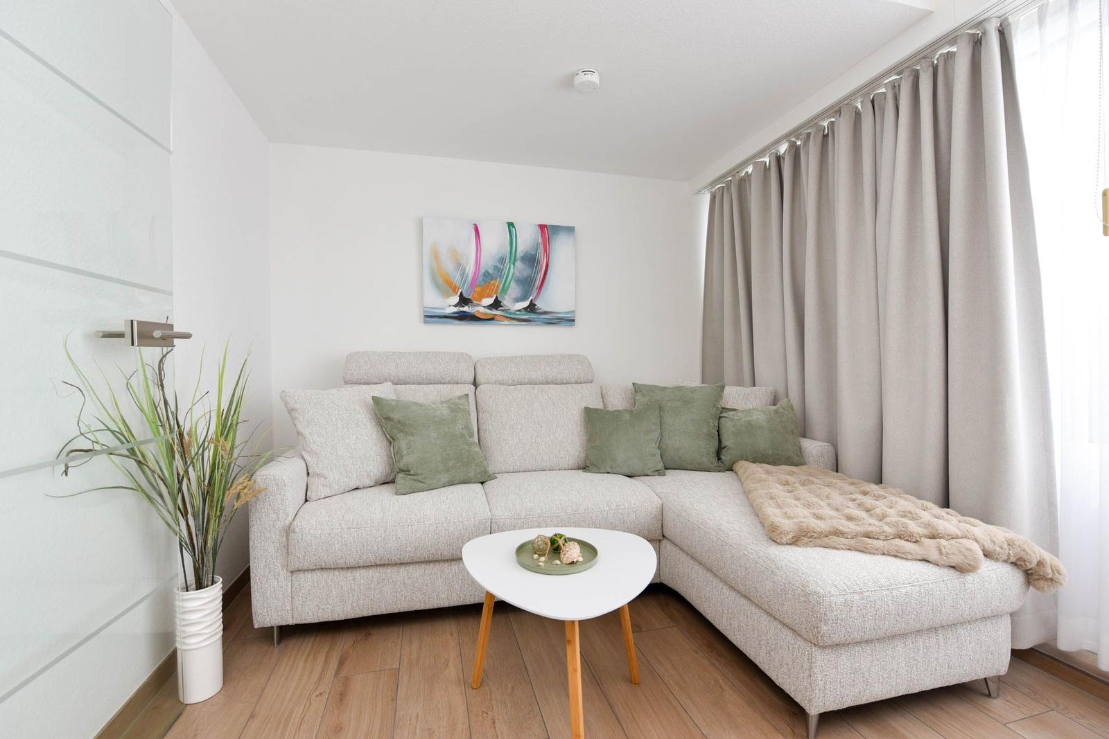 Wohnzimmer mit Ecksofa, Tisch und Bild an der Wand.