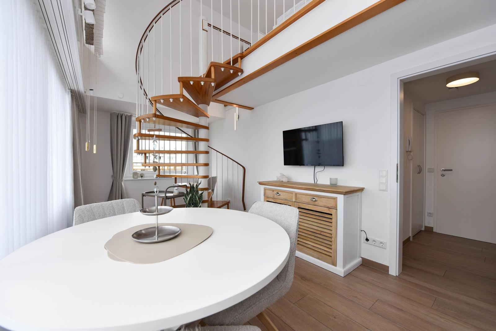 Essbereich mit runder Tisch, Wendeltreppe und Fernseher an Wand