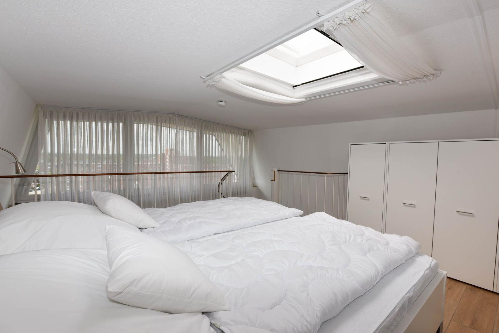Schlafzimmer mit Doppelbett, Fenster und Dachfenster.