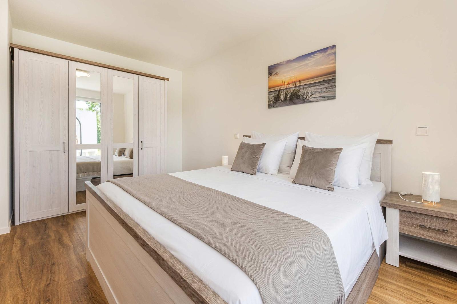 Schlafzimmer mit Doppelbett, Kleiderschrank und Wandbild.
