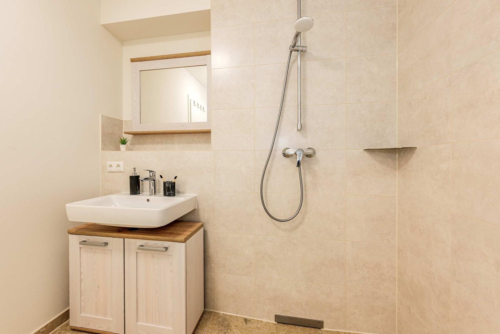 Bad mit Dusche, Waschbecken und Spiegel