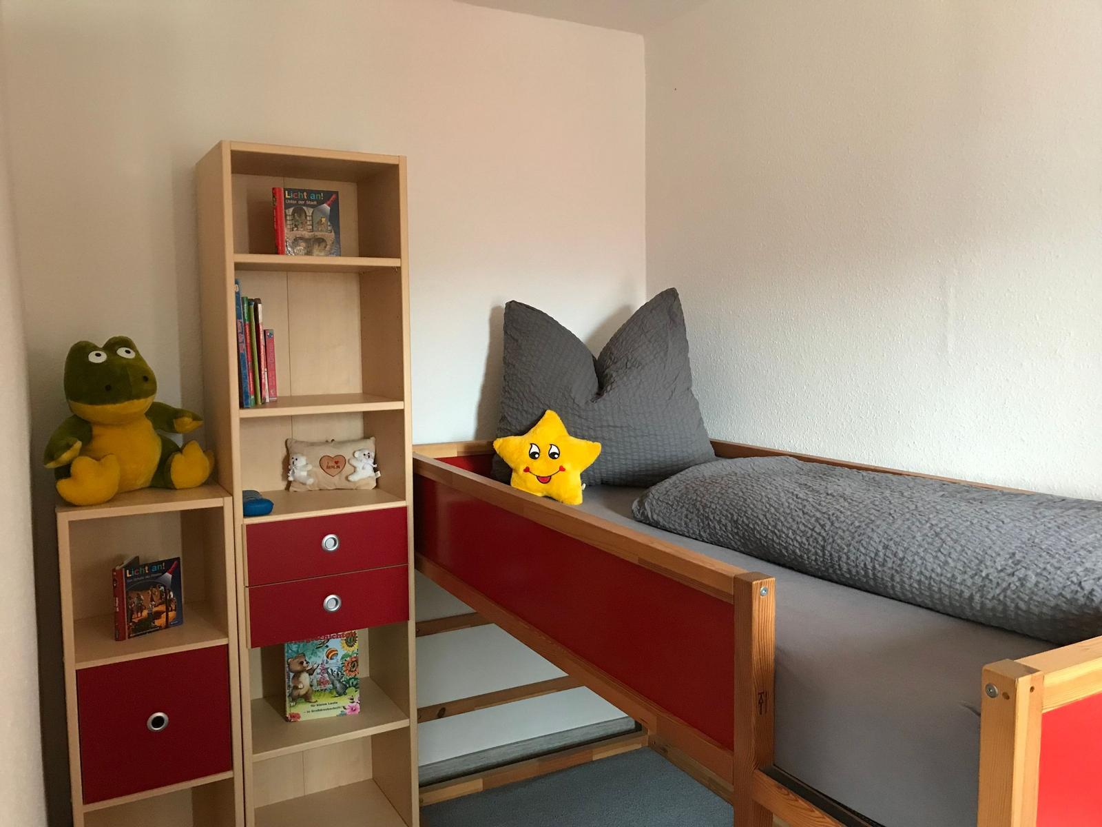 Kinderzimmer mit Bett, Bücherregal und Spielzeug.