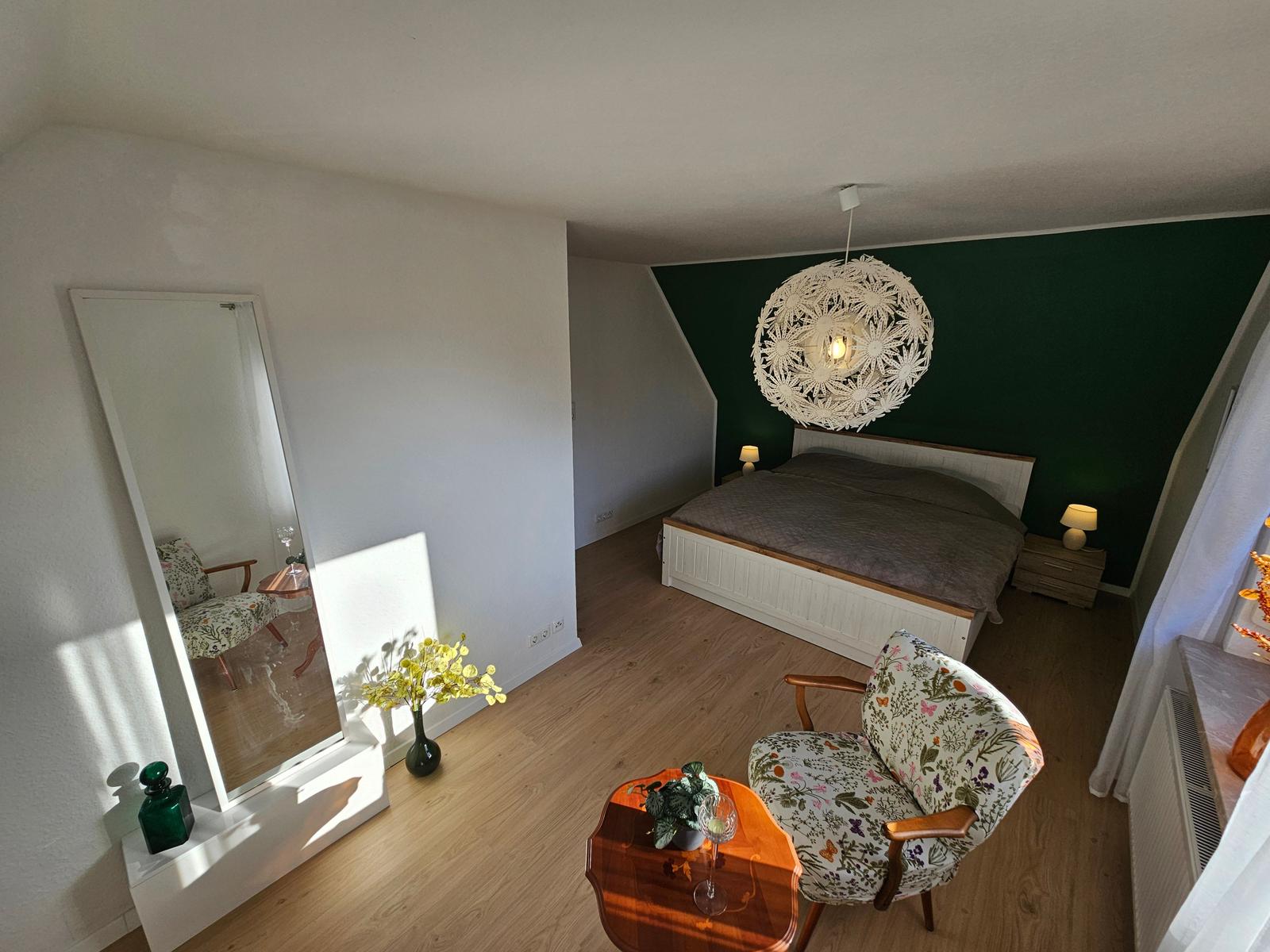 Schlafzimmer mit Bett, Stuhl und Spiegel an der Wand