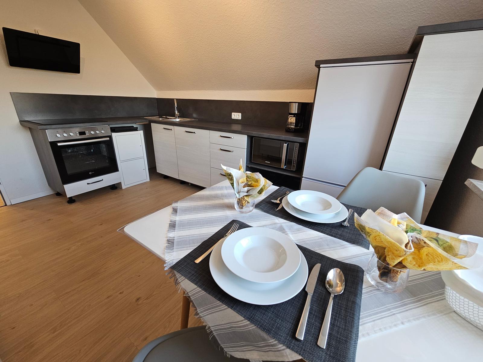 Küche mit Essbereich, Holzboden und schrägen Dachstuhl.
