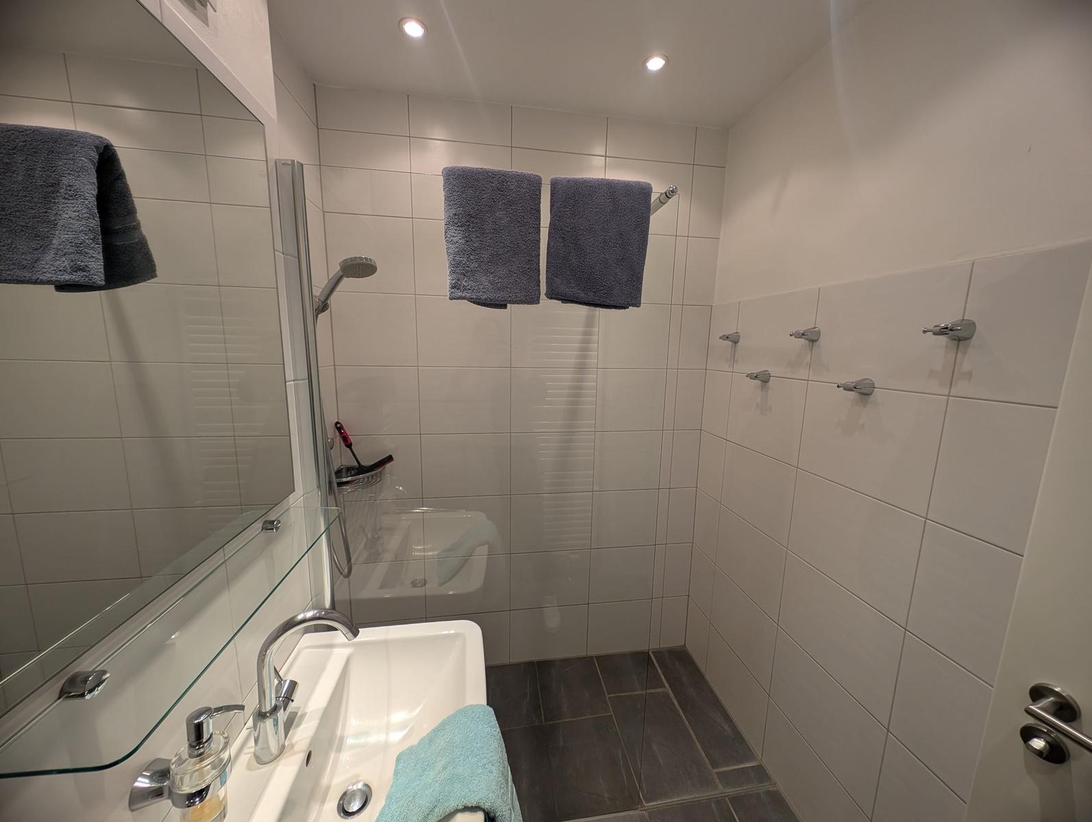 Badezimmer mit Dusche, Waschbecken und Handtüchern.