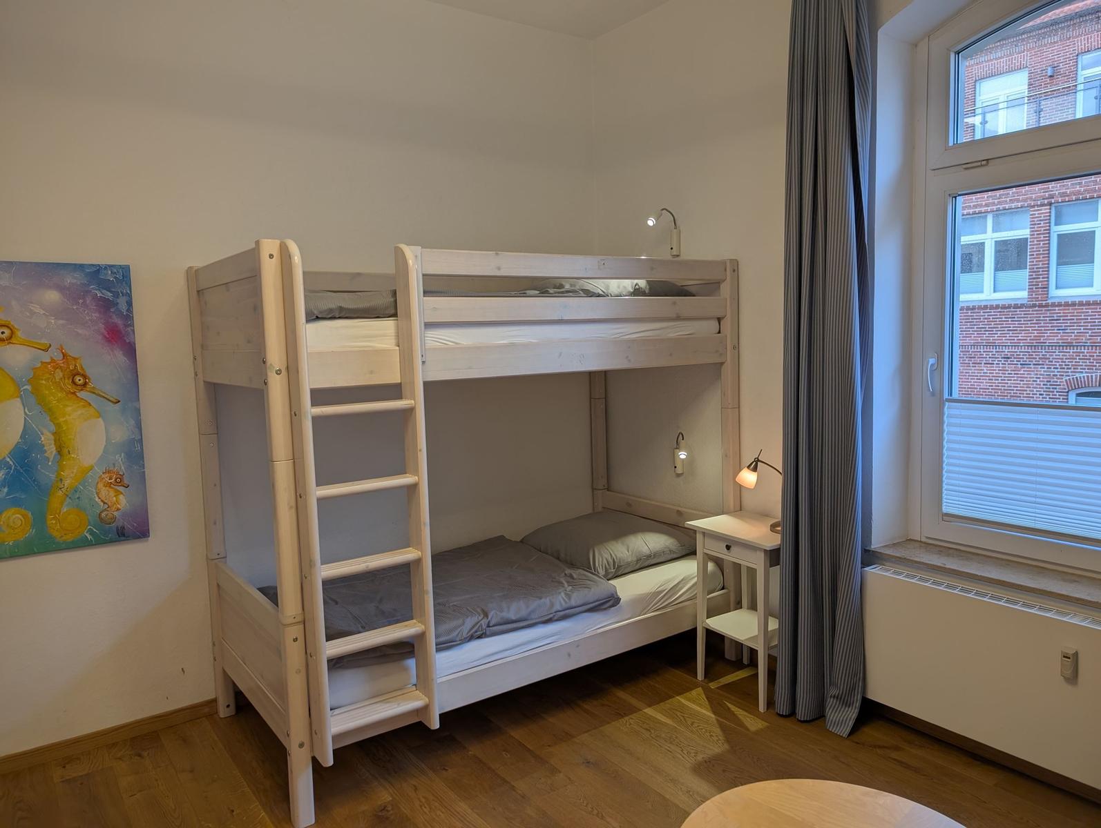Ein Schlafzimmer mit einem Doppelstockbett, einem Nachttisch und einem Fenster.