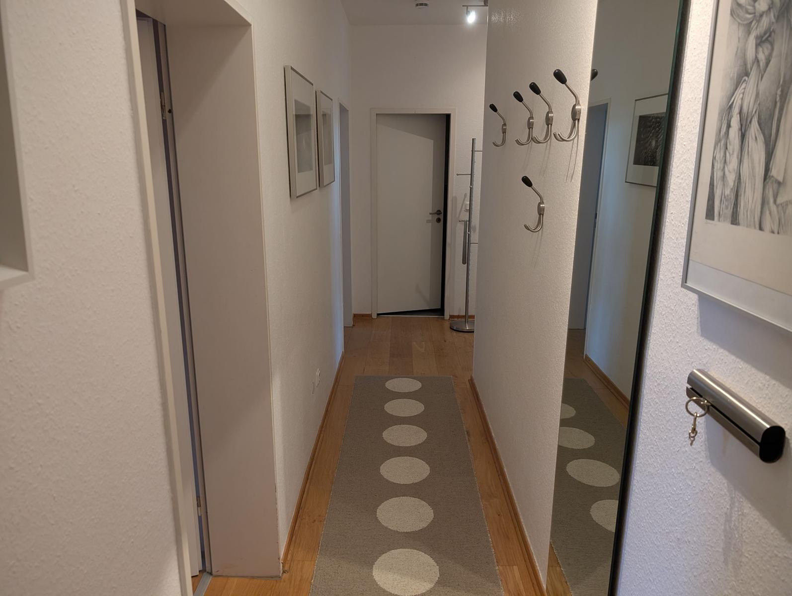 Flur mit Teppich, Kleiderhaken und Bildern an den Wänden.