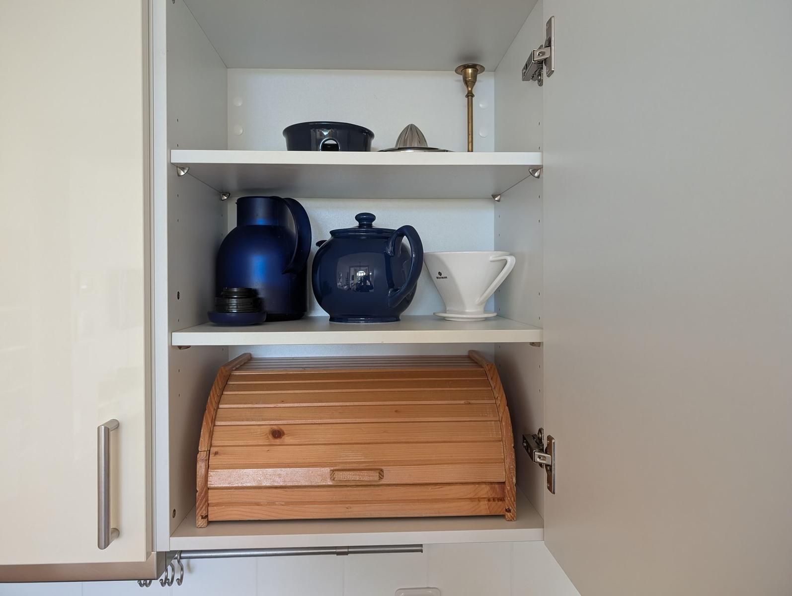 Küchenregal mit blauen Tassen, Kanne und Holzbackofen