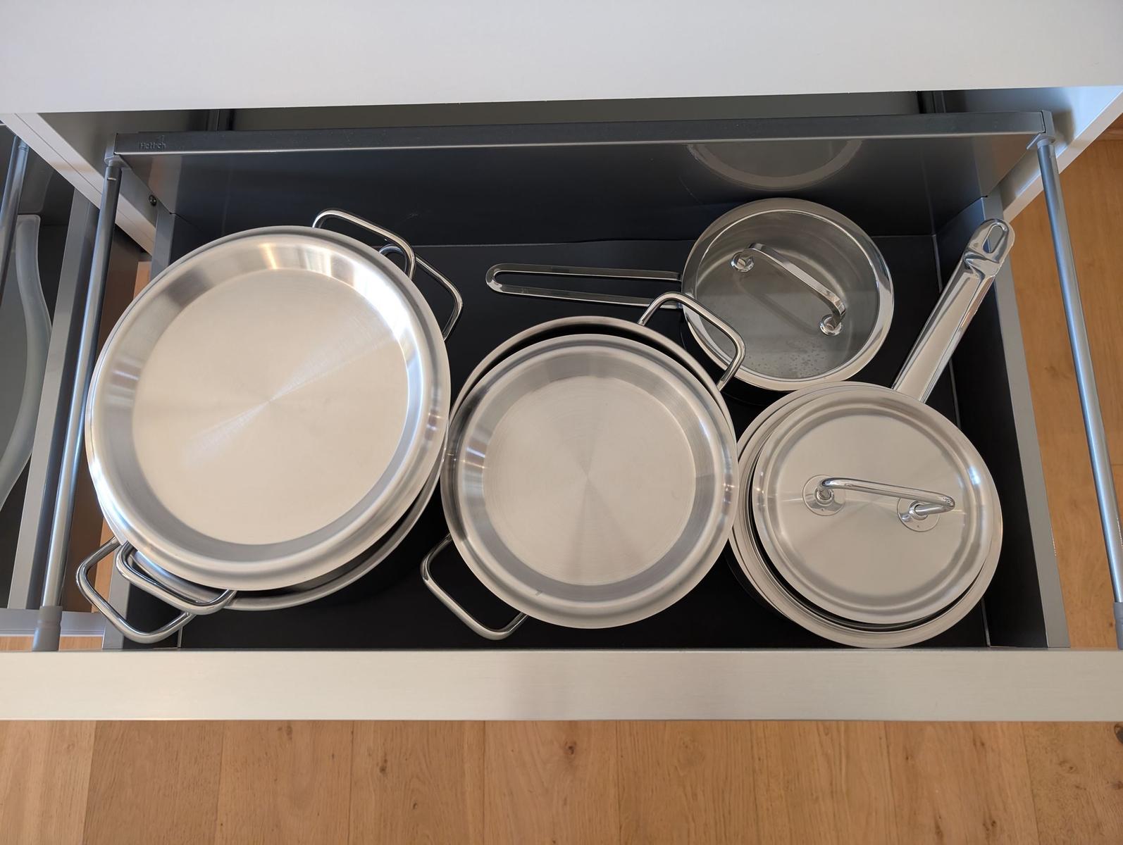 Küchenschrank mit Edelstahl-Pfannen und Deckeln