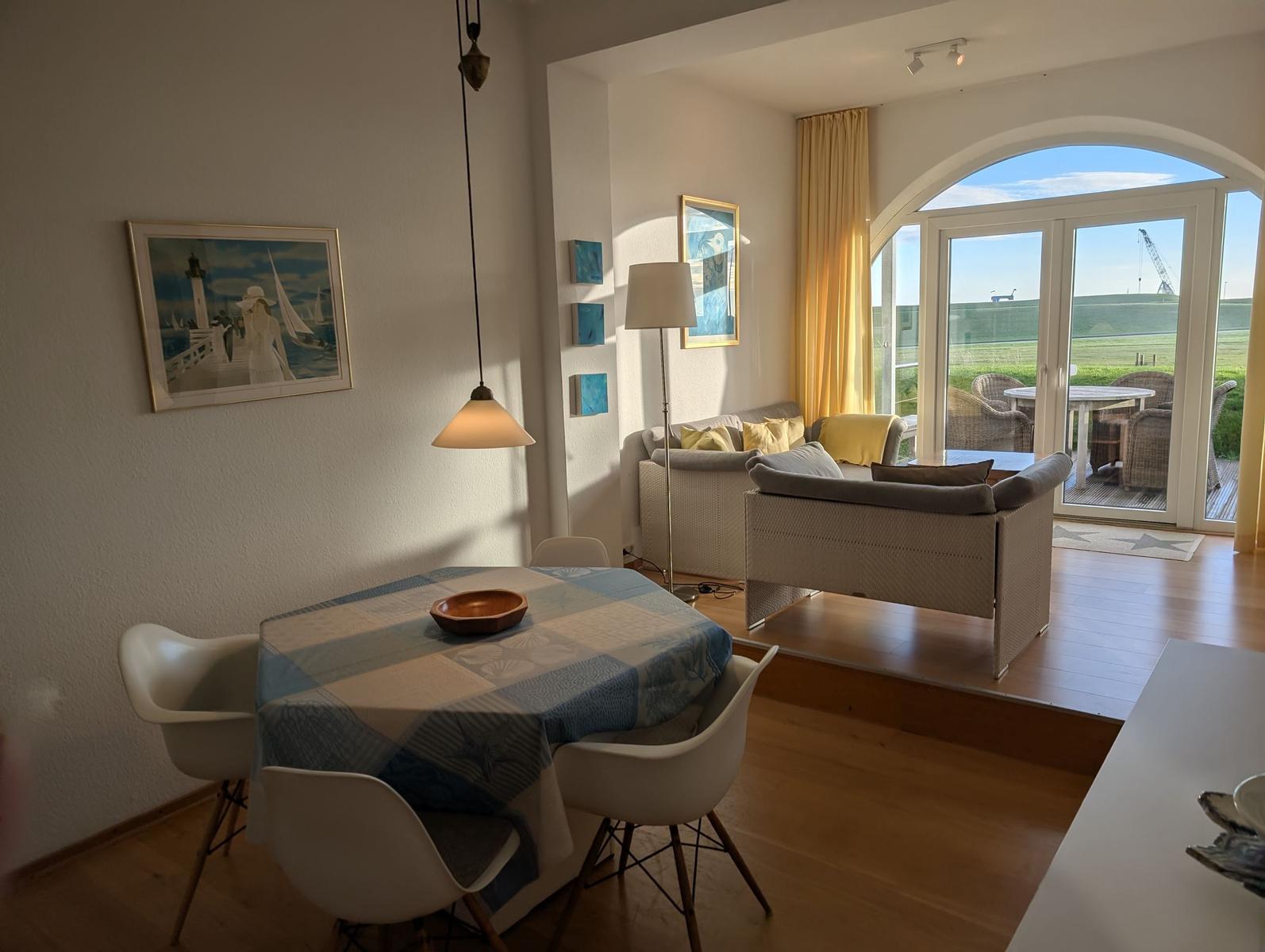 Essbereich mit Tisch und Stühlen. Wohnbereich mit Sofa und Blick auf Terrasse.