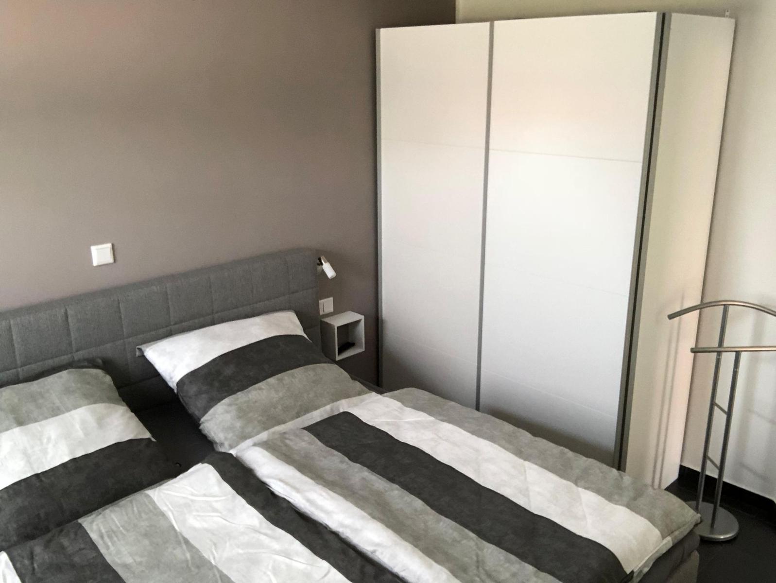 Schlafzimmer mit Doppelbett, Kleiderschrank und Stehlampe.