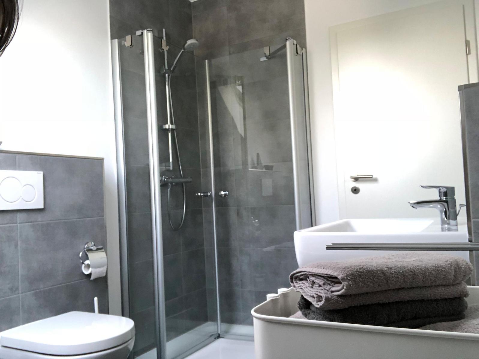 Badezimmer mit Dusche, Waschbecken und Toilette. Handtuch auf Waschbecken.