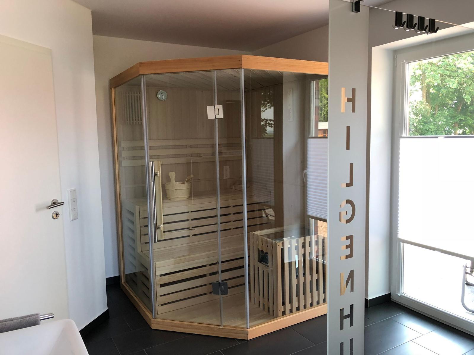 Sauna mit Glaswänden und Holzbank. Fenster mit Blick auf Grün.