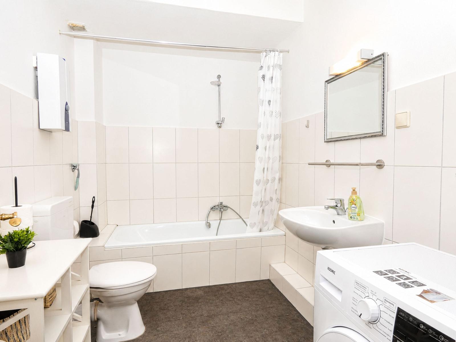 Badezimmer mit Badewanne, Waschmaschine und Toilette.