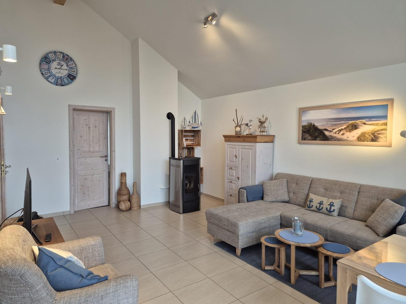 Wohnzimmer mit Sofa, Kaminofen und Küchenbereich.