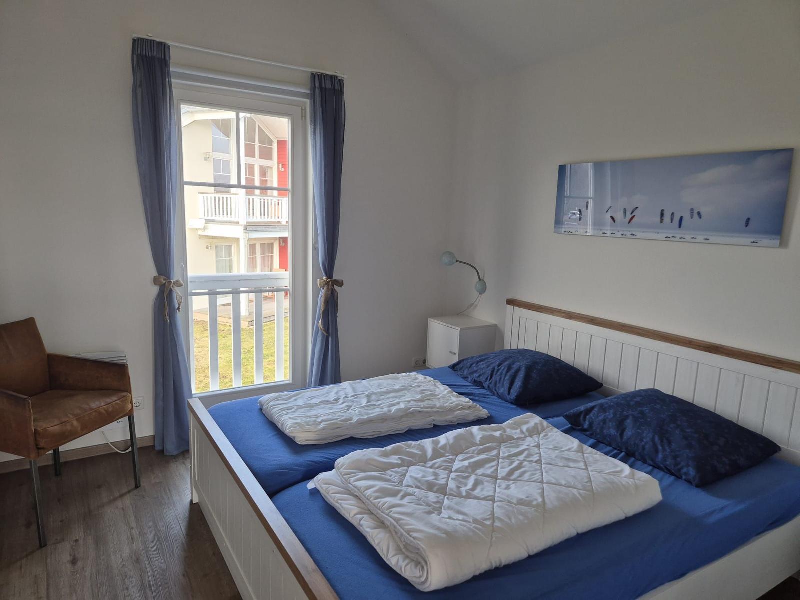 Schlafzimmer mit Doppelbett, Fenster mit Balkon und Wandbild.
