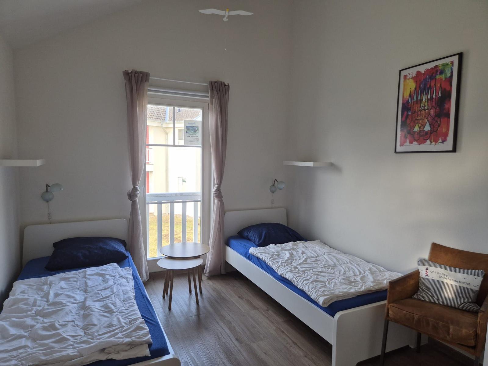 Zwei Einzelbetten, Fenster mit Balkon, Stuhl und Wandbild.