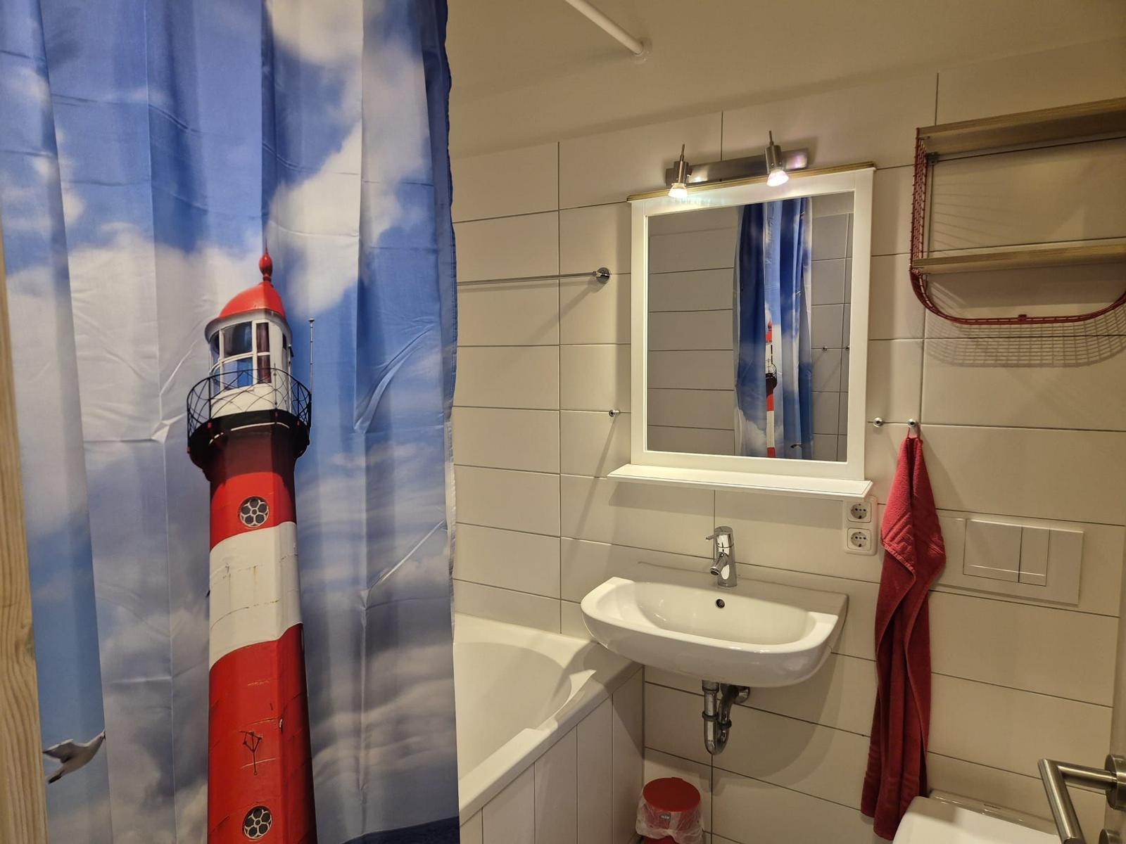Badezimmer mit Duschvorhang, Waschbecken und Spiegel