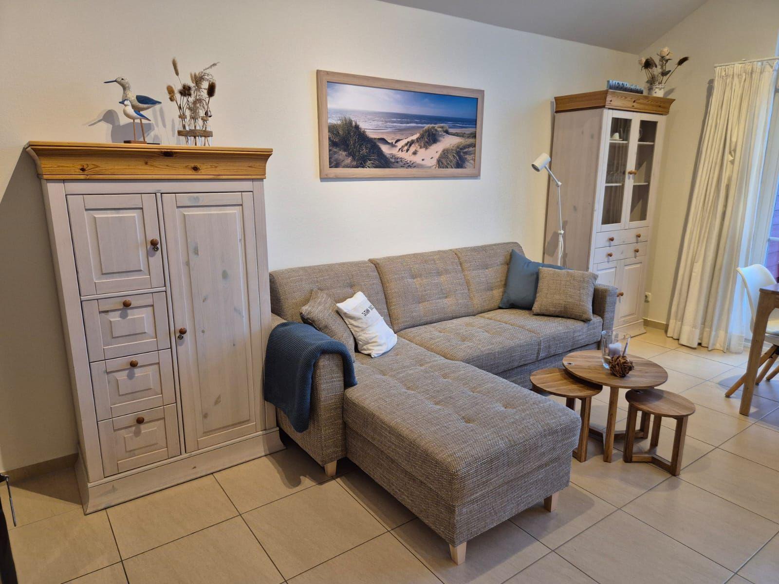Wohnzimmer mit Sofa, Holzmöbel und Strandbild an der Wand.