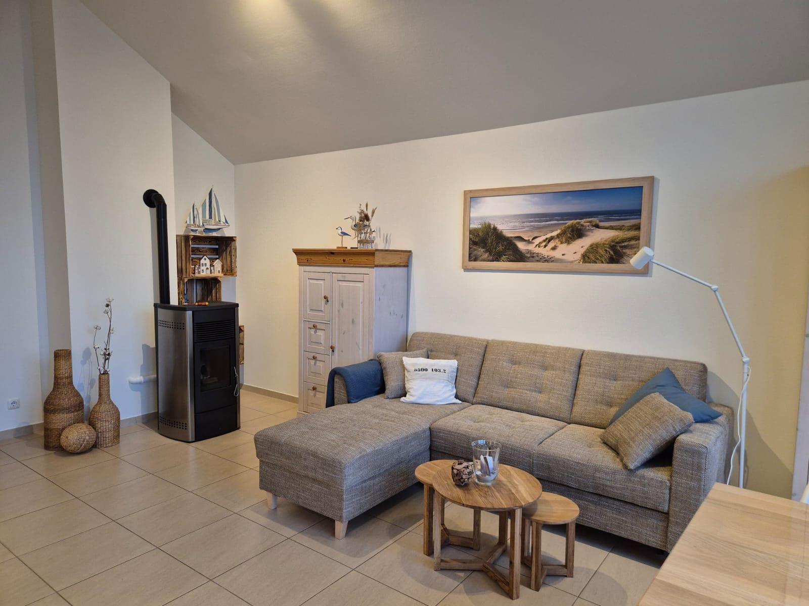 Wohnzimmer mit Sofa, Kaminofen und Wandbild