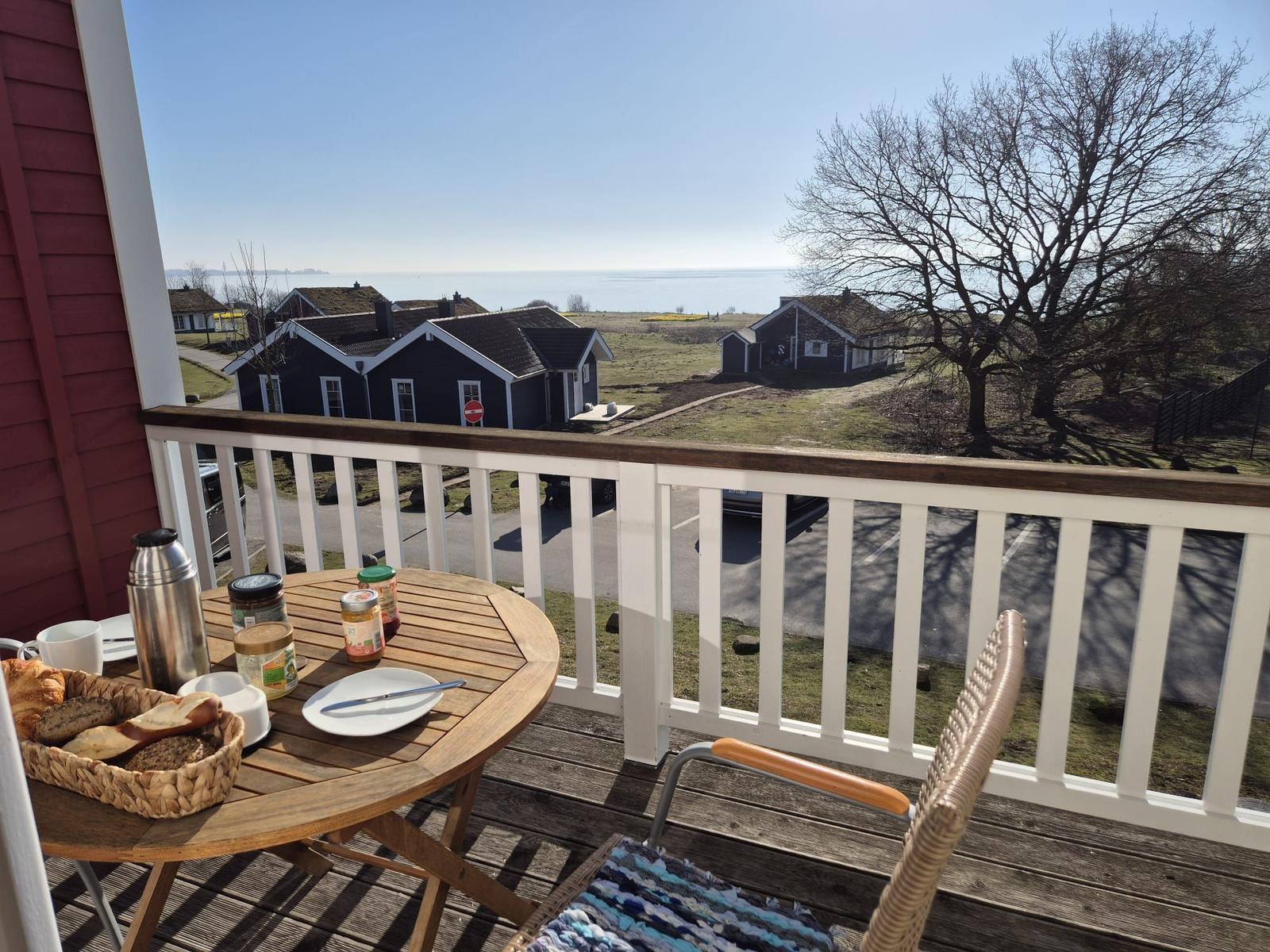 Terrasse mit Tisch und Stuhl, Blick auf Häuser und Meer.