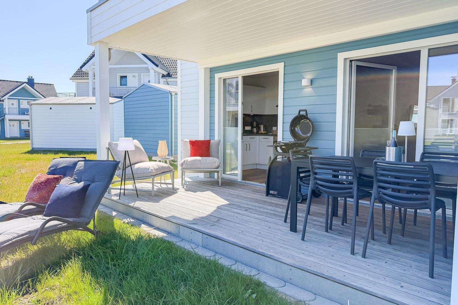 Terrasse mit Sitzgelegenheiten, Grill und Blick in die Küche.