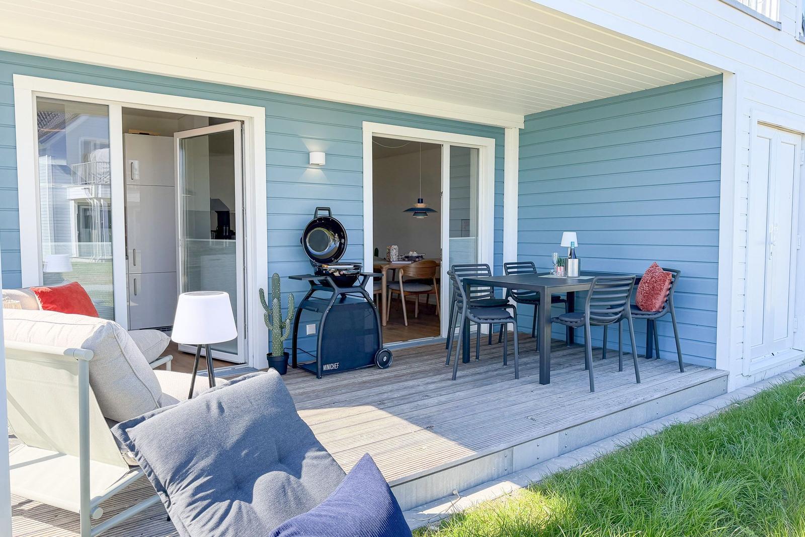 Terrasse mit Sitzgelegenheiten, Grill und Blick ins Haus.