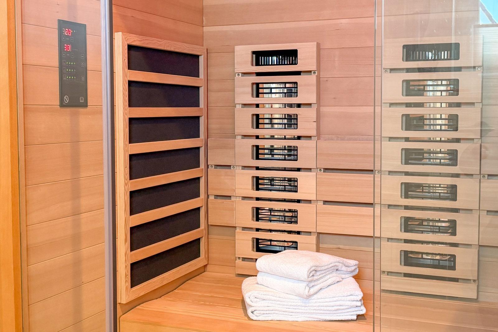 Sauna mit Holzwand, Heizung und gefalteten Handtüchern.