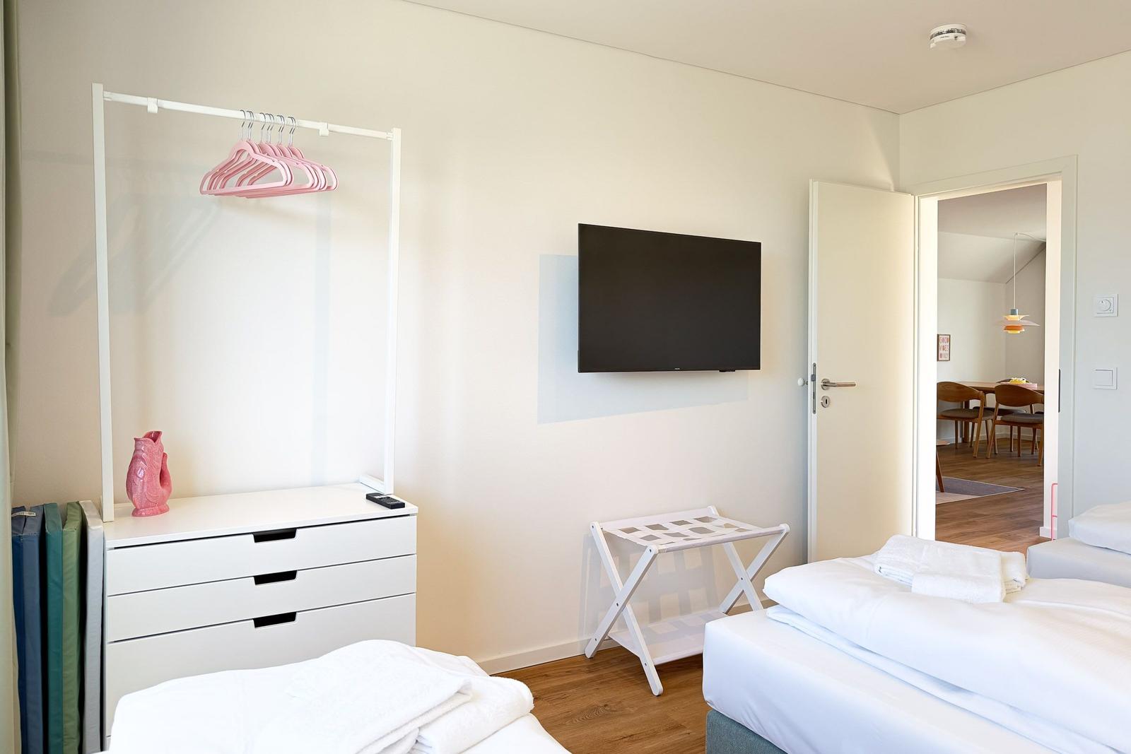 Schlafzimmer mit Bett, Kleiderschrank und Fernseher. Tür führt in Esszimmer.