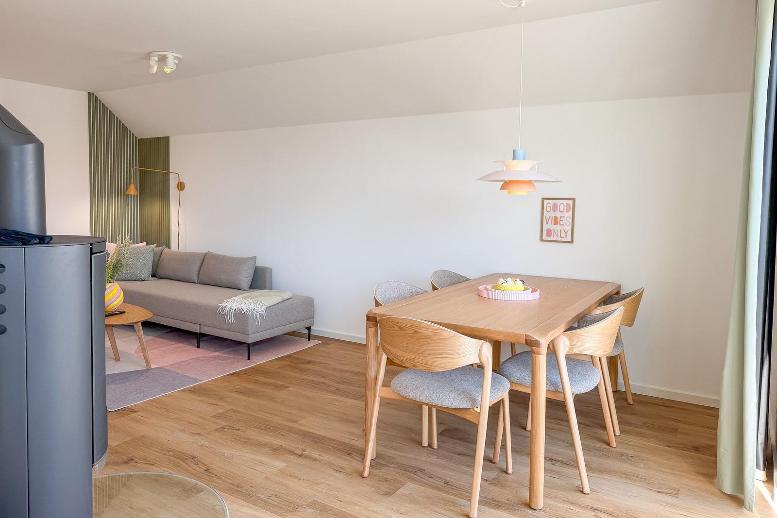 Essbereich mit Holztisch und Stühlen. Wohnbereich mit Sofa und Teppich.