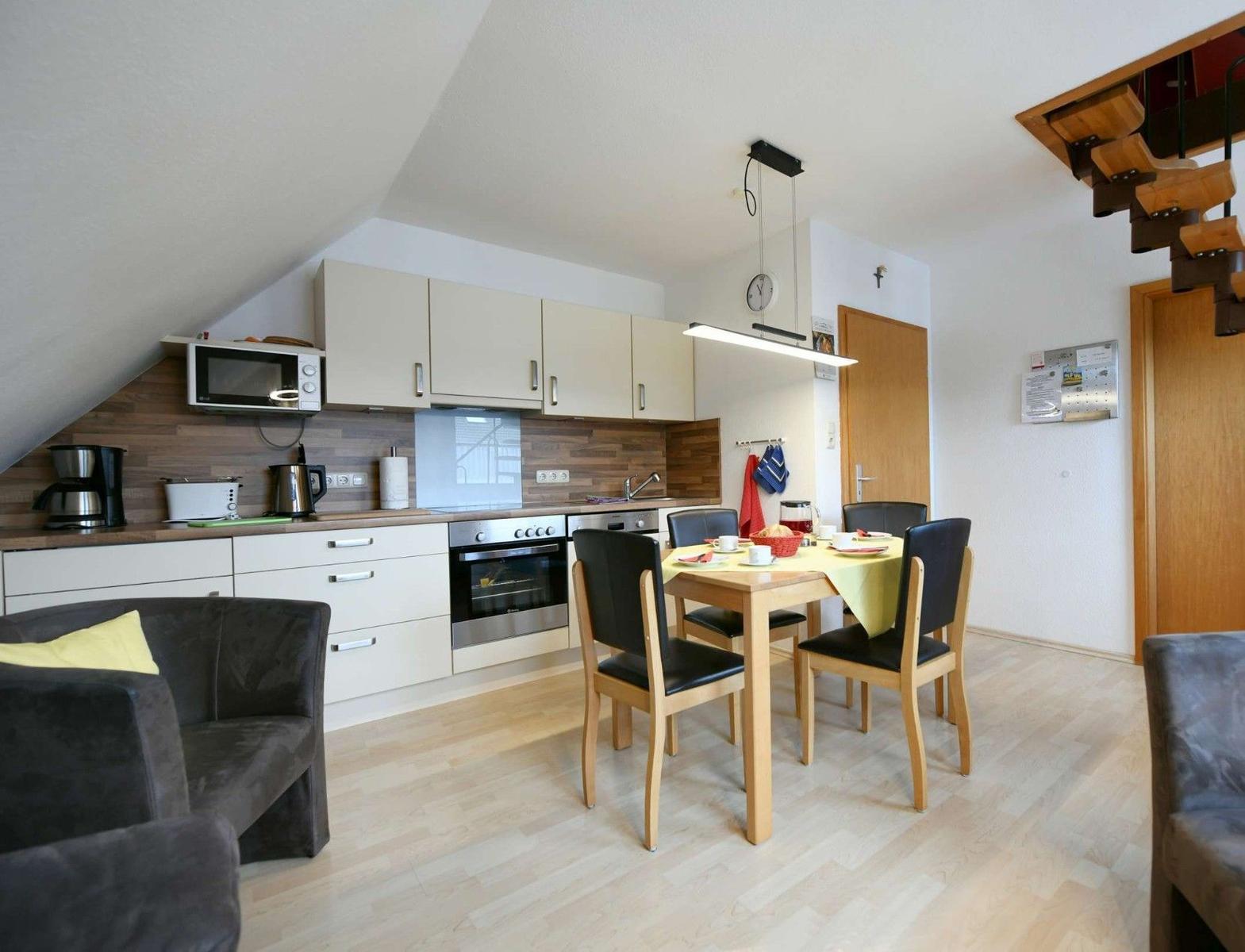 Küche mit Essbereich, Sofa und Treppe zur oberen Etage.