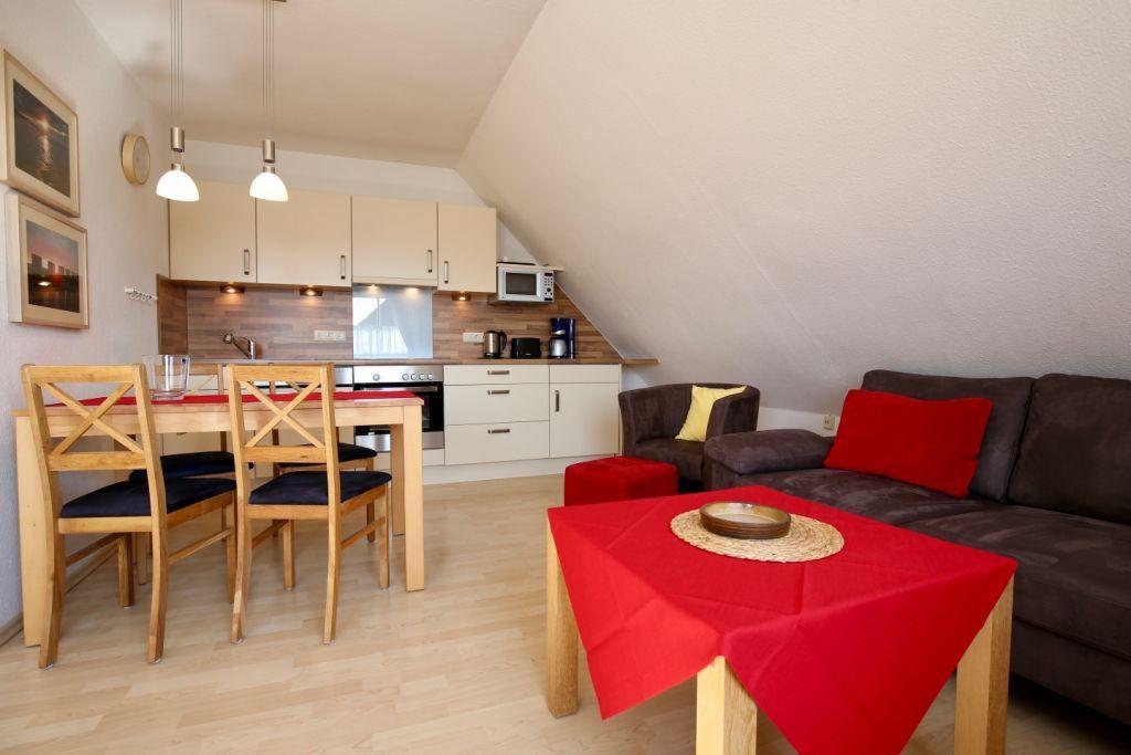 Wohnung mit Küche, Essbereich und Sofa unter Dachschrägen.