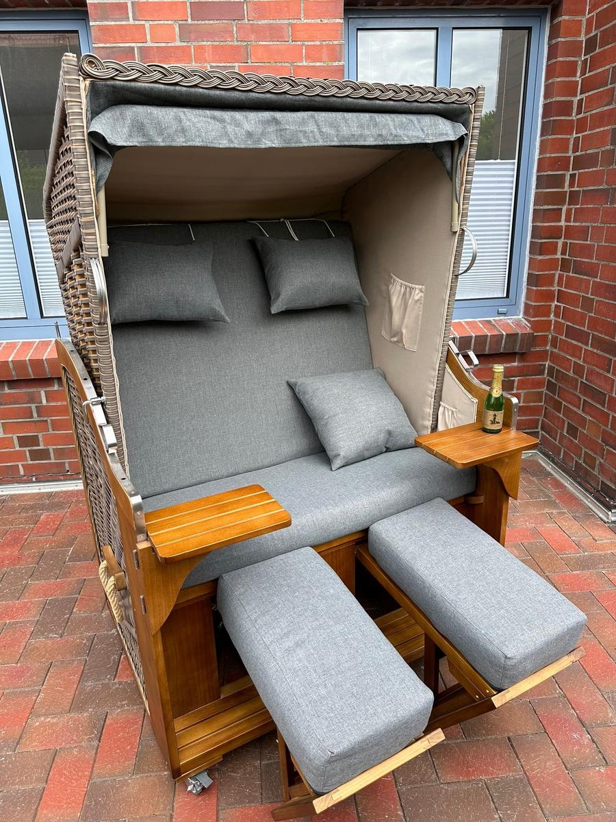 Hochwertige Strandliege mit grauer Polsterung und Holztablett auf Terrasse.