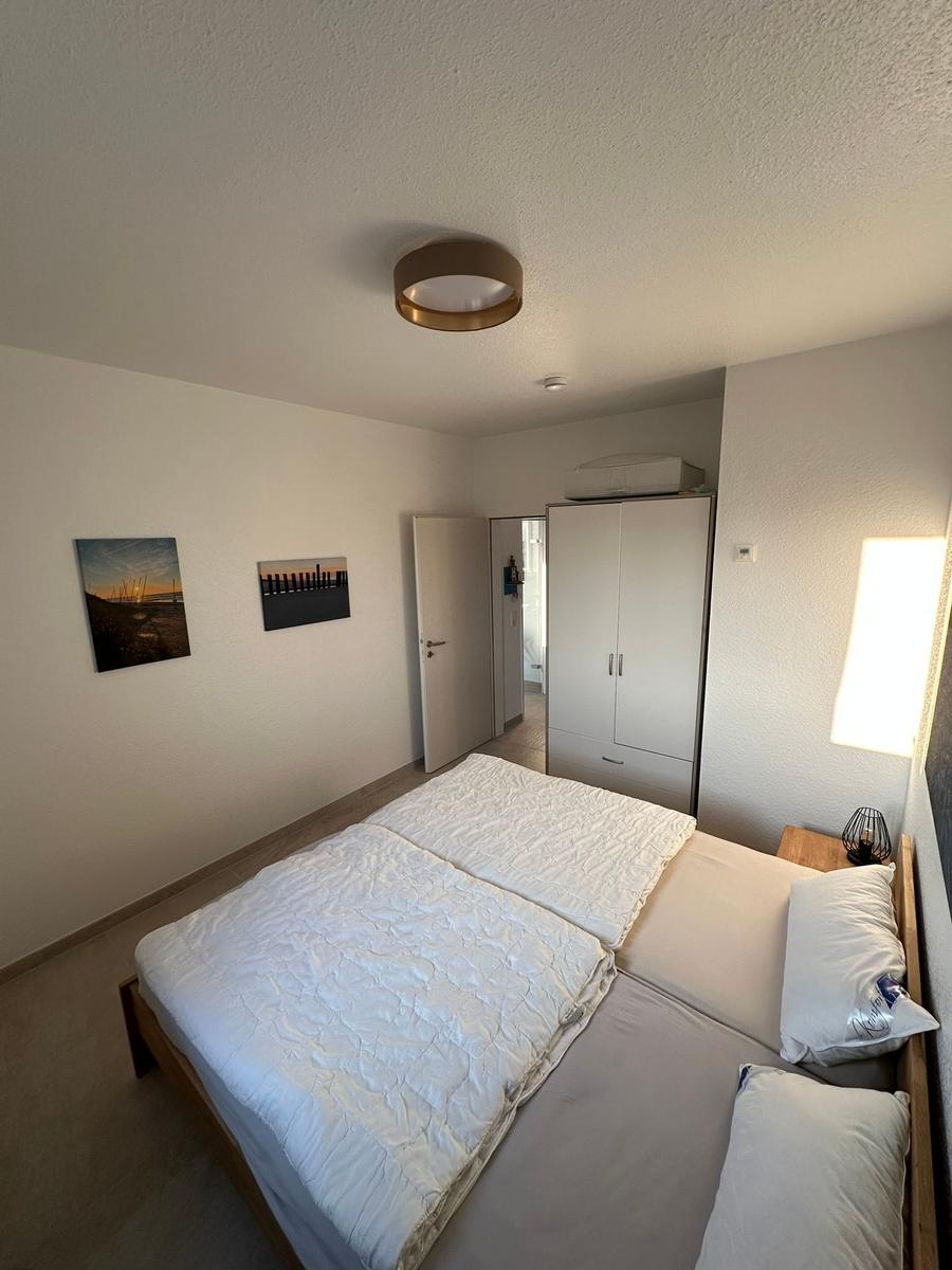 Schlafzimmer mit Doppelbett, Kleiderschrank und zwei Wandbildern.