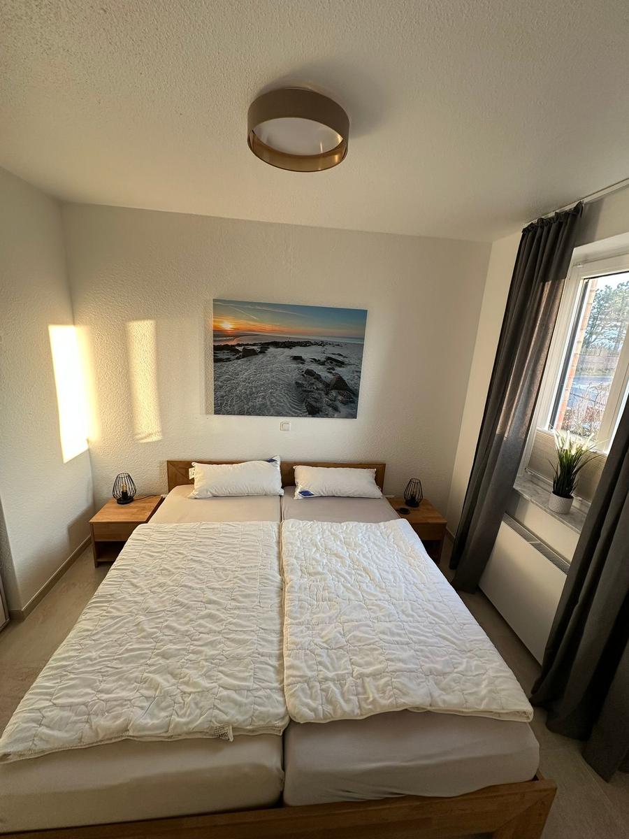 Schlafzimmer mit Doppelbett, Wandbild und Fenster mit Blick.