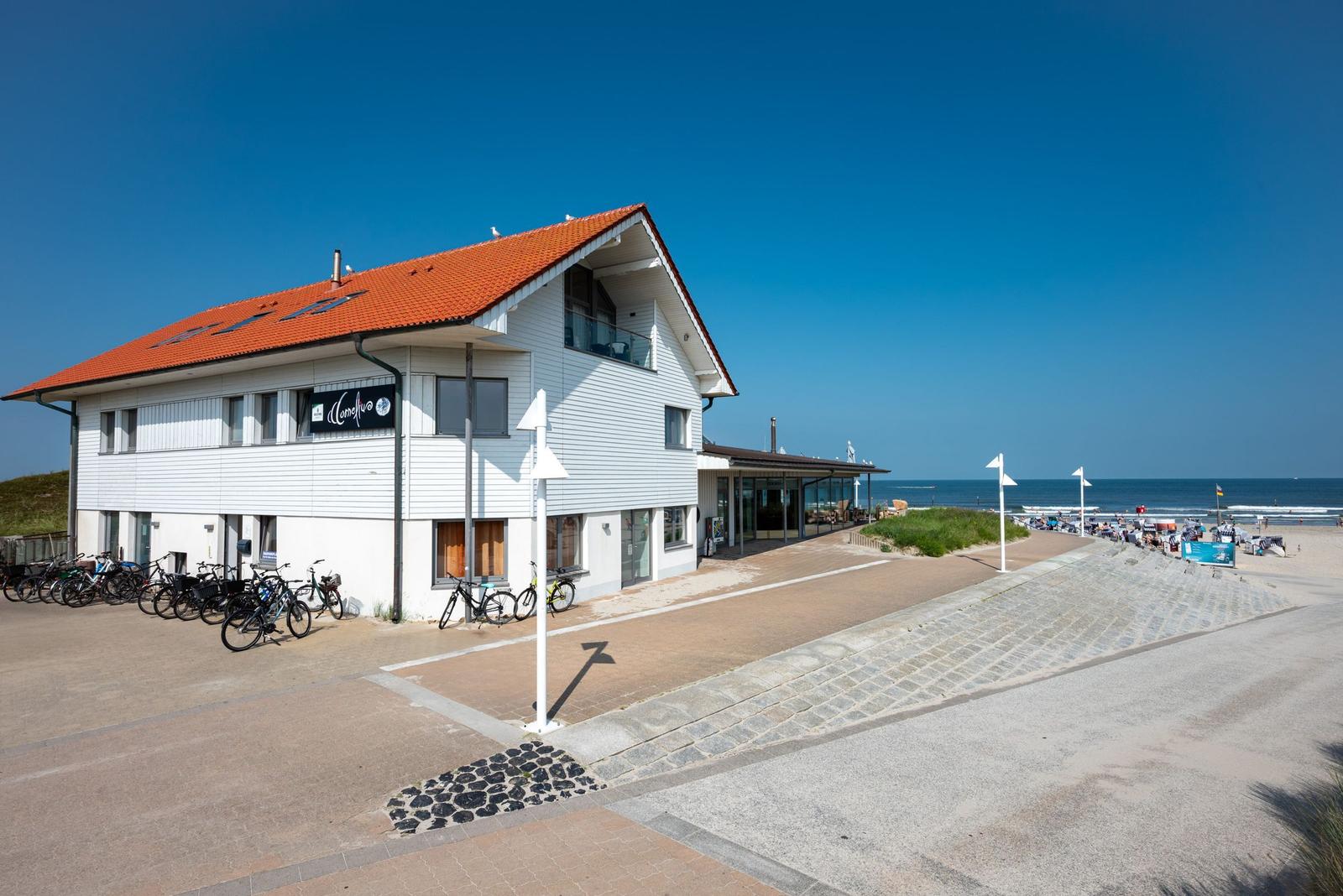 Modernes Haus mit rotem Dach und Fahrradstellplätzen direkt am Strand.