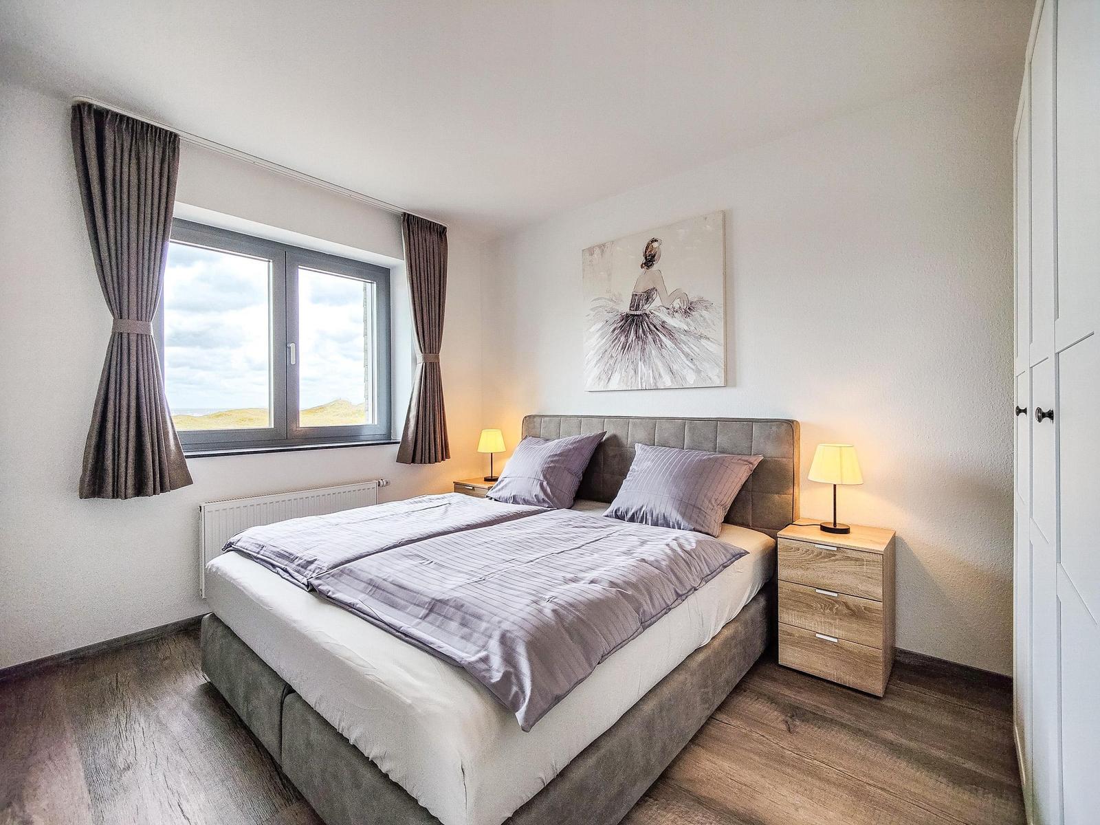 Schlafzimmer mit Doppelbett, Fenster mit Blick und Nachttischen.