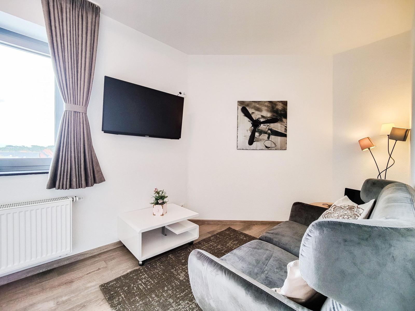 Wohnzimmer mit Sofa, Fernseher und Wandbild