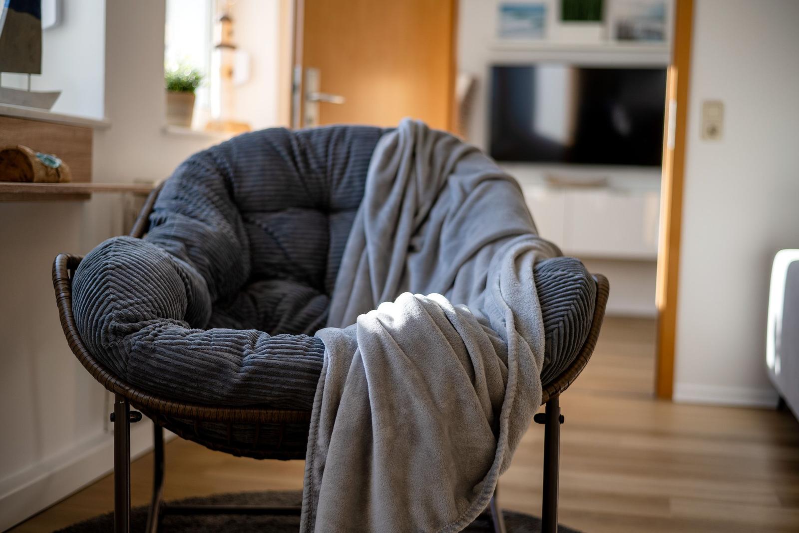 Ein Sessel mit Kissen und Decke im Wohnzimmer.