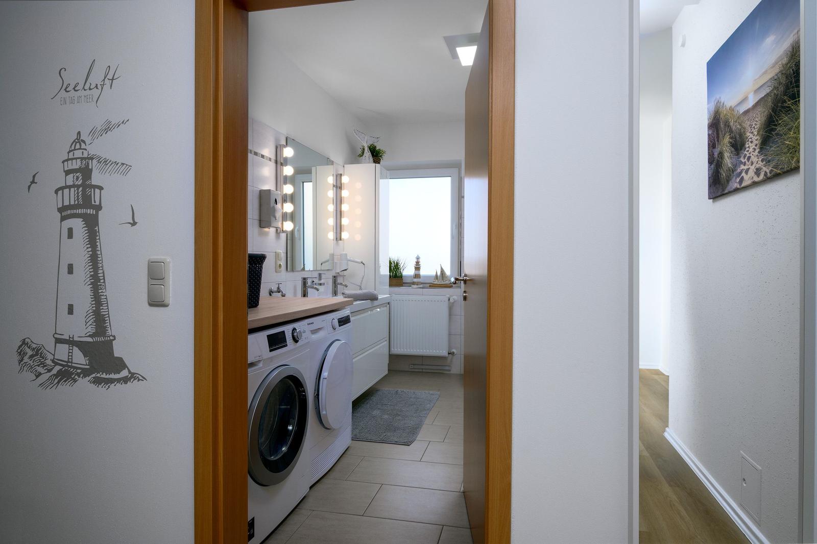 Badezimmer mit Waschmaschine, Spiegel und Fenster