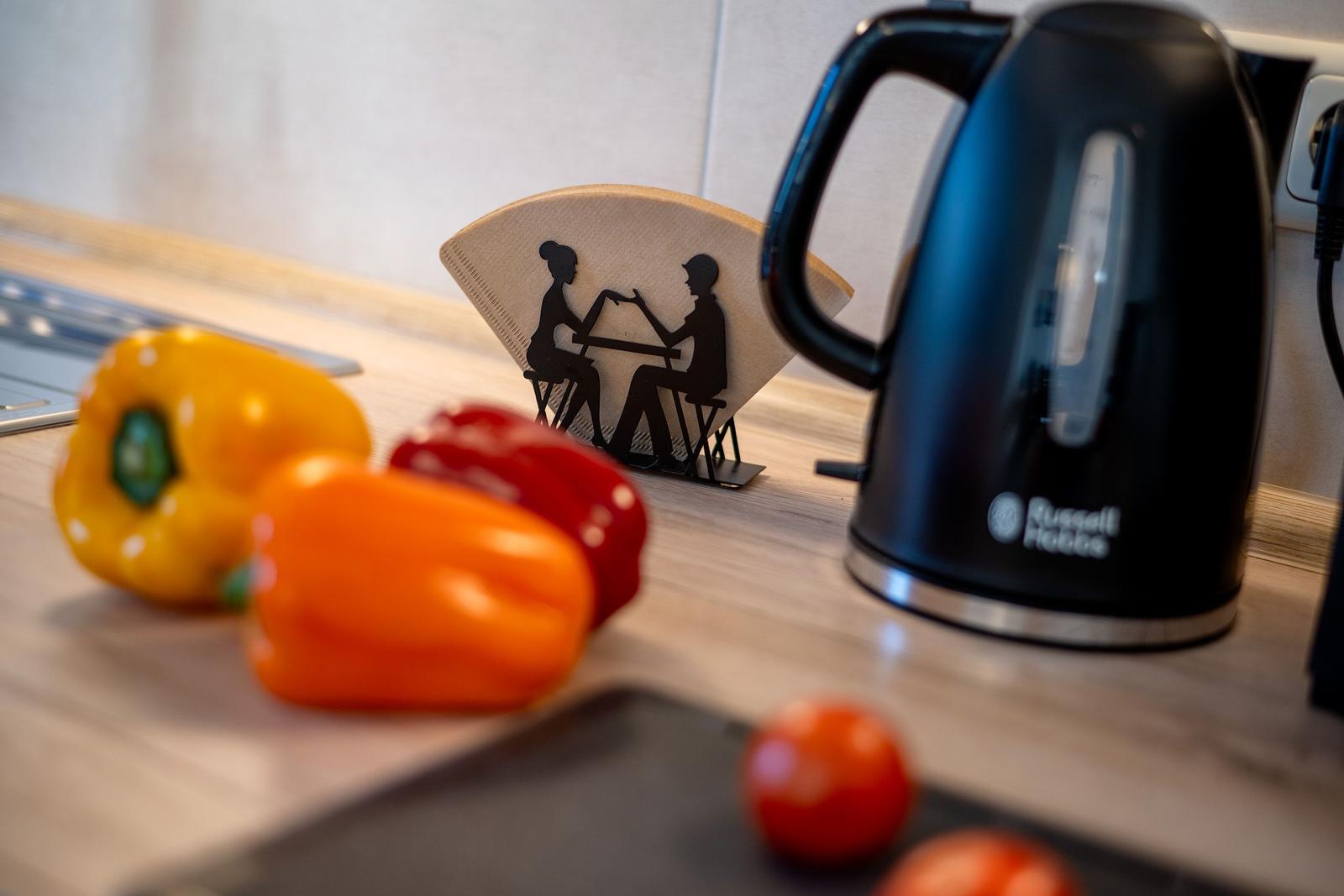 Küchenarbeitsfläche mit Kaffeekanne, Paprika und Tomaten.