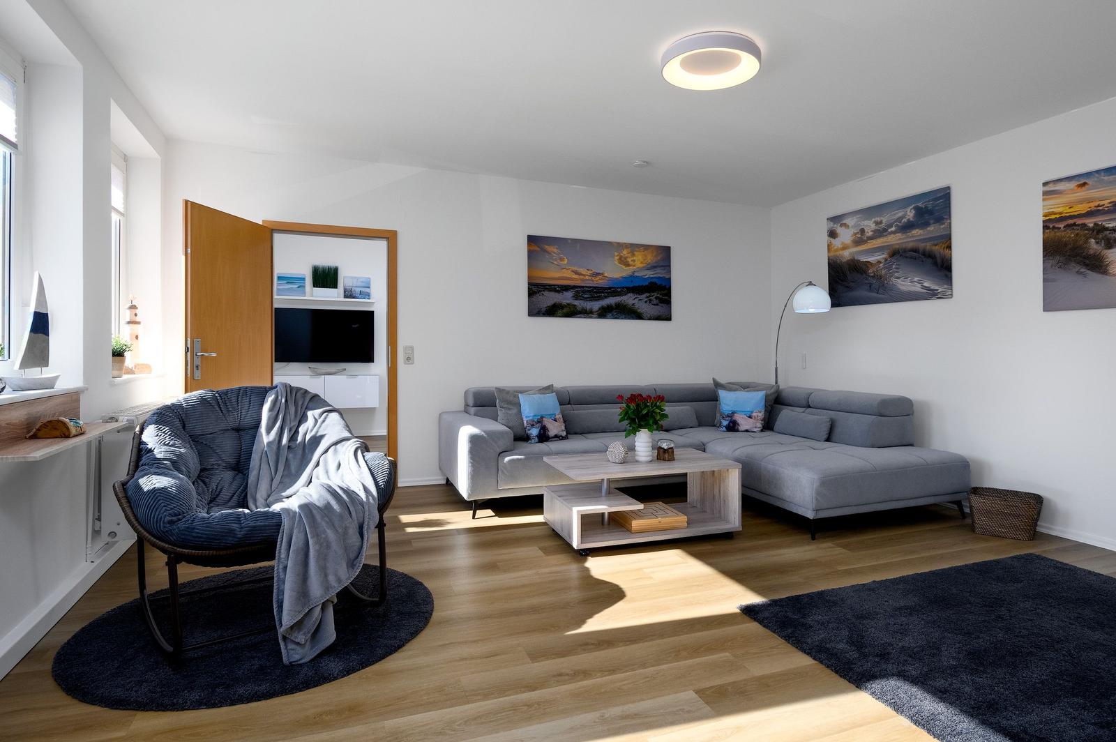 Wohnzimmer mit grauem Sofa, Holzboden und Wandbildern