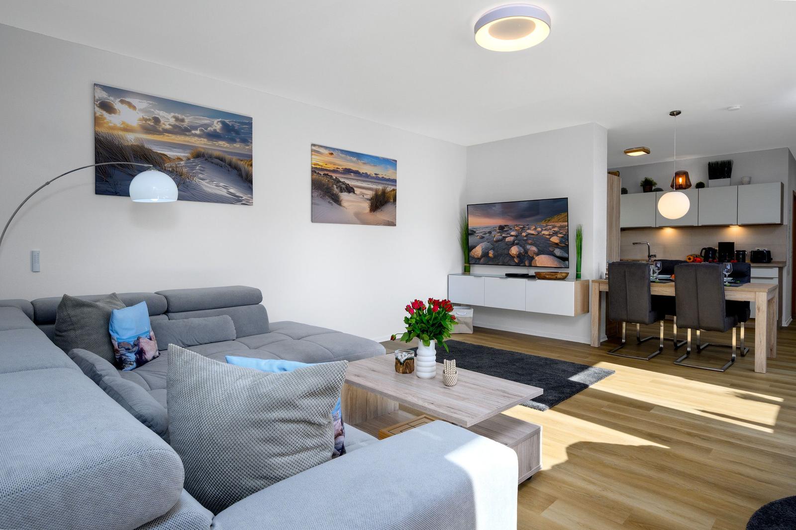 Wohn- und Essbereich mit Sofa, Fernseher und Küchenzeile.