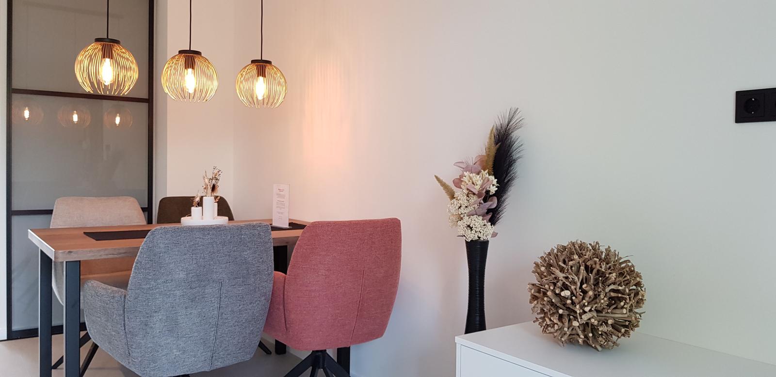 Esstisch mit Stühlen und hängenden Lampen. Dekorative Pflanzen auf einem Sideboard.