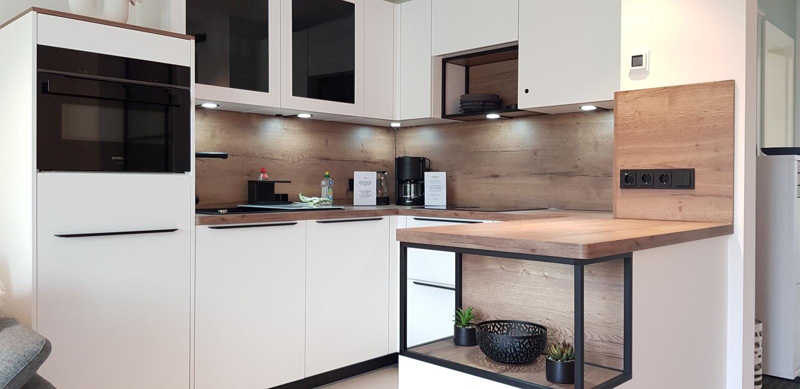 Moderne Küche mit Holzoberflächen und weißen Schränken. Arbeitsfläche mit integriertem Kühlschrank.