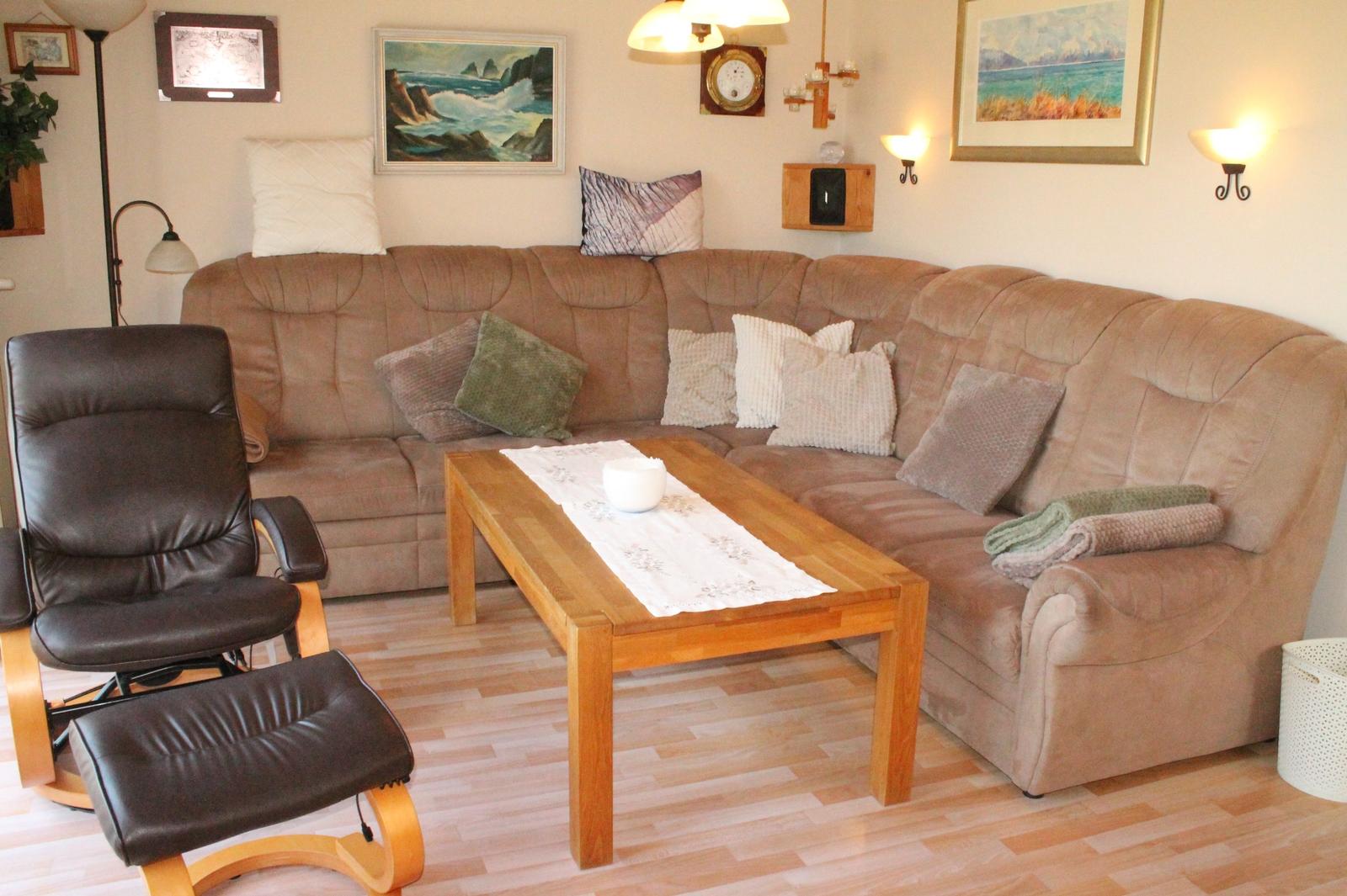 Ein Wohnzimmer mit einem braunen Sofa, einem Holztisch und einem schwarzen Sessel.